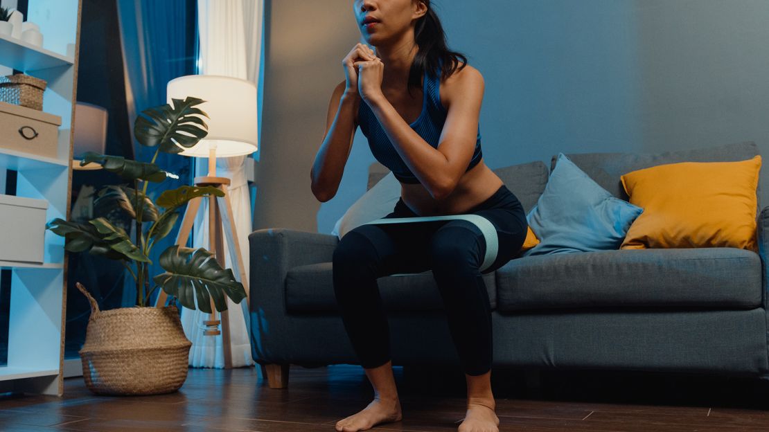 Chair squats target the quadriceps, hamstrings and glutes. Adding a resistance band above the knees can help you maintain form.